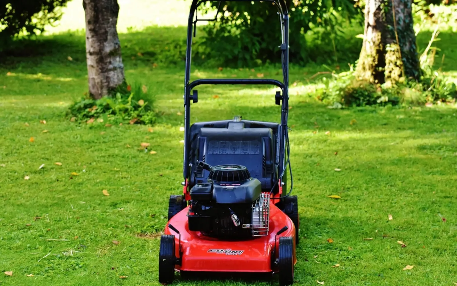A red lawn mower on a green lawn
